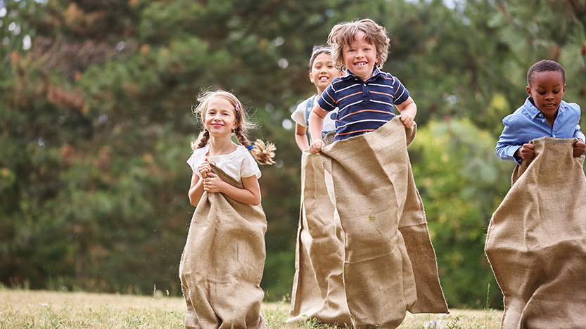 Crianças divertem-se a fazer uma gincana - corrida de sacos