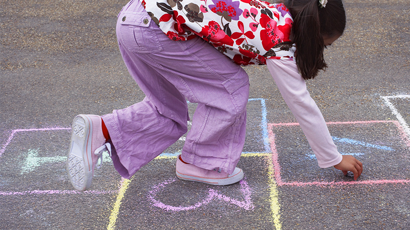 Menina diverte-se a brincar ao jogo da macaca